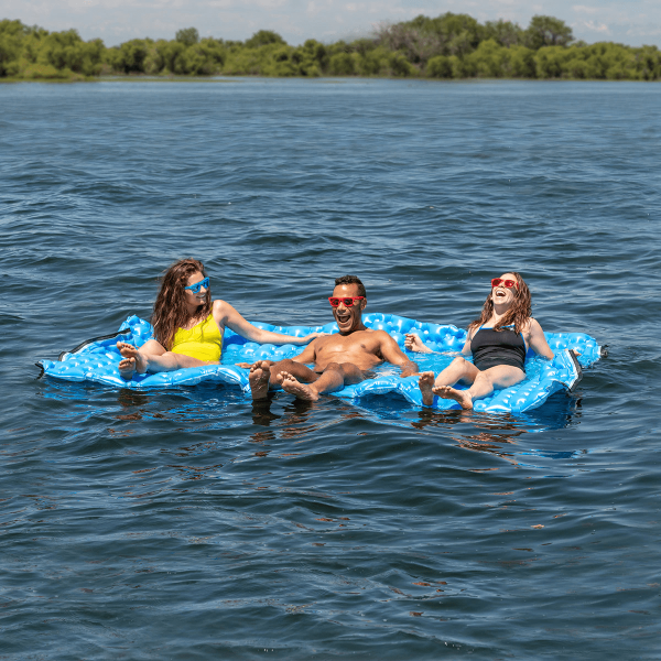 Action shot of three adults lounging on the Air Island while in the water