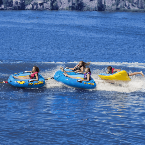 Action shot of four people riding the sea monster towable tube
