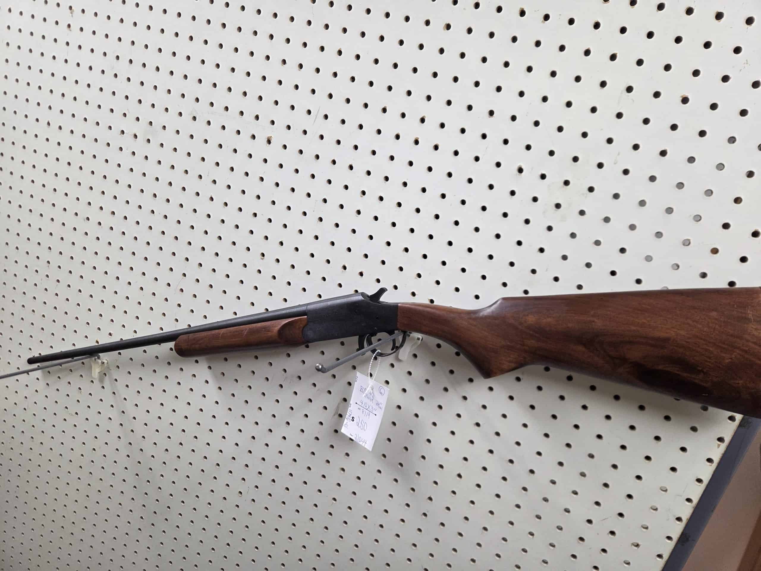 Boito 2 Product 1000014577, a single-barrel break-action shotgun with a wooden stock, hangs on a pegboard wall with a price tag attached to the trigger guard.