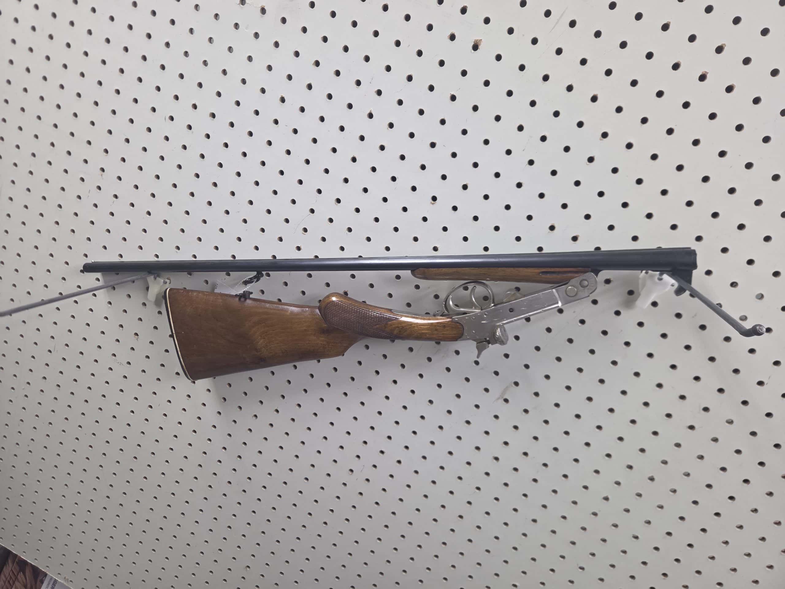 El Faisan 1 Break-action shotgun 20261018_093014 with a wooden stock mounted on a pegboard wall.